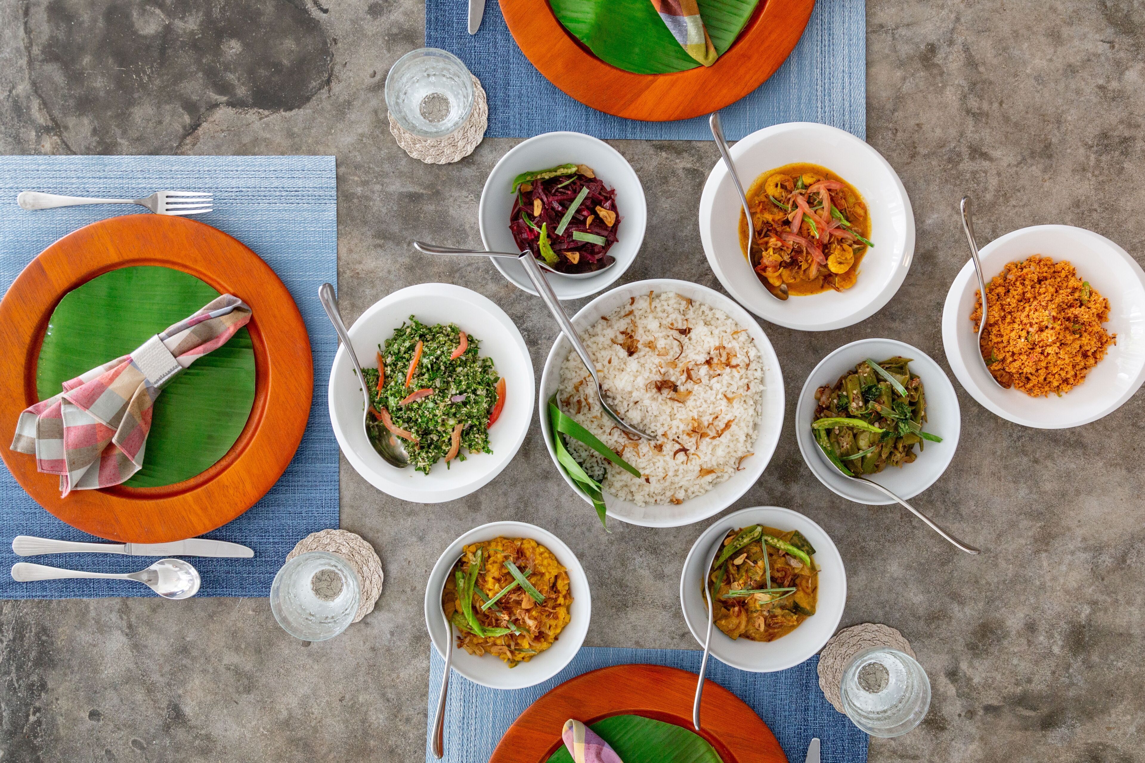 A table set with various dishes, utensils, and a blue placemat.