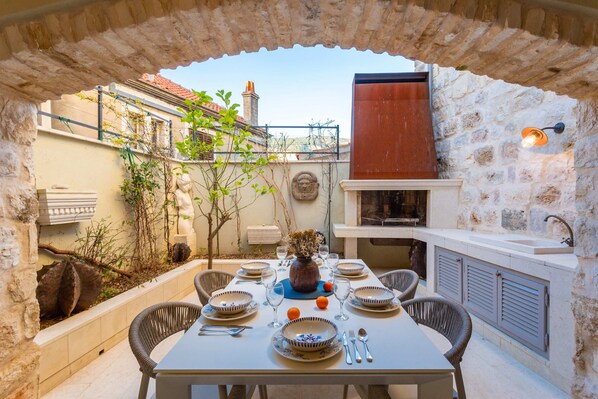 An outdoor dining area with stone walls, a grill, and a view of the city.