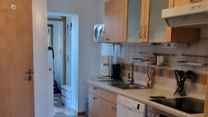 Une cuisine avec un carrelage à motifs, des meubles en bois, un lave-vaisselle blanc et une cuisinière.