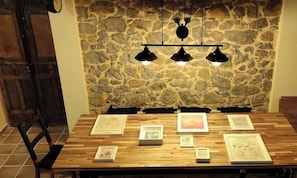 A wooden table with framed artworks and a stone wall background. - Find the north in the "House of the good way". (Oreña)