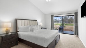 A bedroom with a large bed, a nightstand, a TV, and a sliding glass door leading to an outdoor area. - 3BR Golf Villa Near Beach & Fairway Views (Pawleys Island)