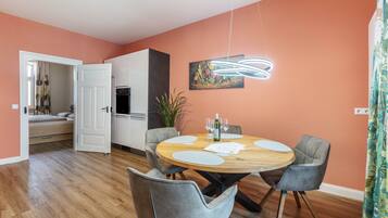 A dining area with a round wooden table, grey upholstered chairs, and a modern pendant light.