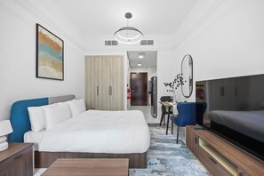 A hotel room with a bed, bedside tables, a TV, a desk with a chair, a wardrobe, and a painting on the wall. - Bloomfields Stunning STU The Gate Masdar (Abu Dhabi)