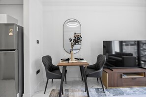 A modern kitchen with a built-in refrigerator, a dining table with two chairs, a mirror, and a flat-screen TV. - Bloomfields Stunning STU The Gate Masdar (Abu Dhabi)