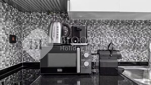 Una cucina con forno a microonde, tostapane e macchina del caffè su un piano di lavoro nero.