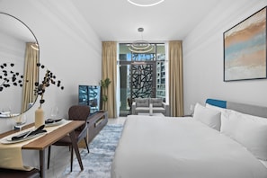 Ein Hotelzimmer mit Bett, Schreibtisch, Stuhl, Esstisch, einem großen Spiegel und Blick auf die Stadt.