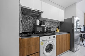 Eine moderne Küche mit Waschmaschine, Kaffeemaschine und Kühlschrank.