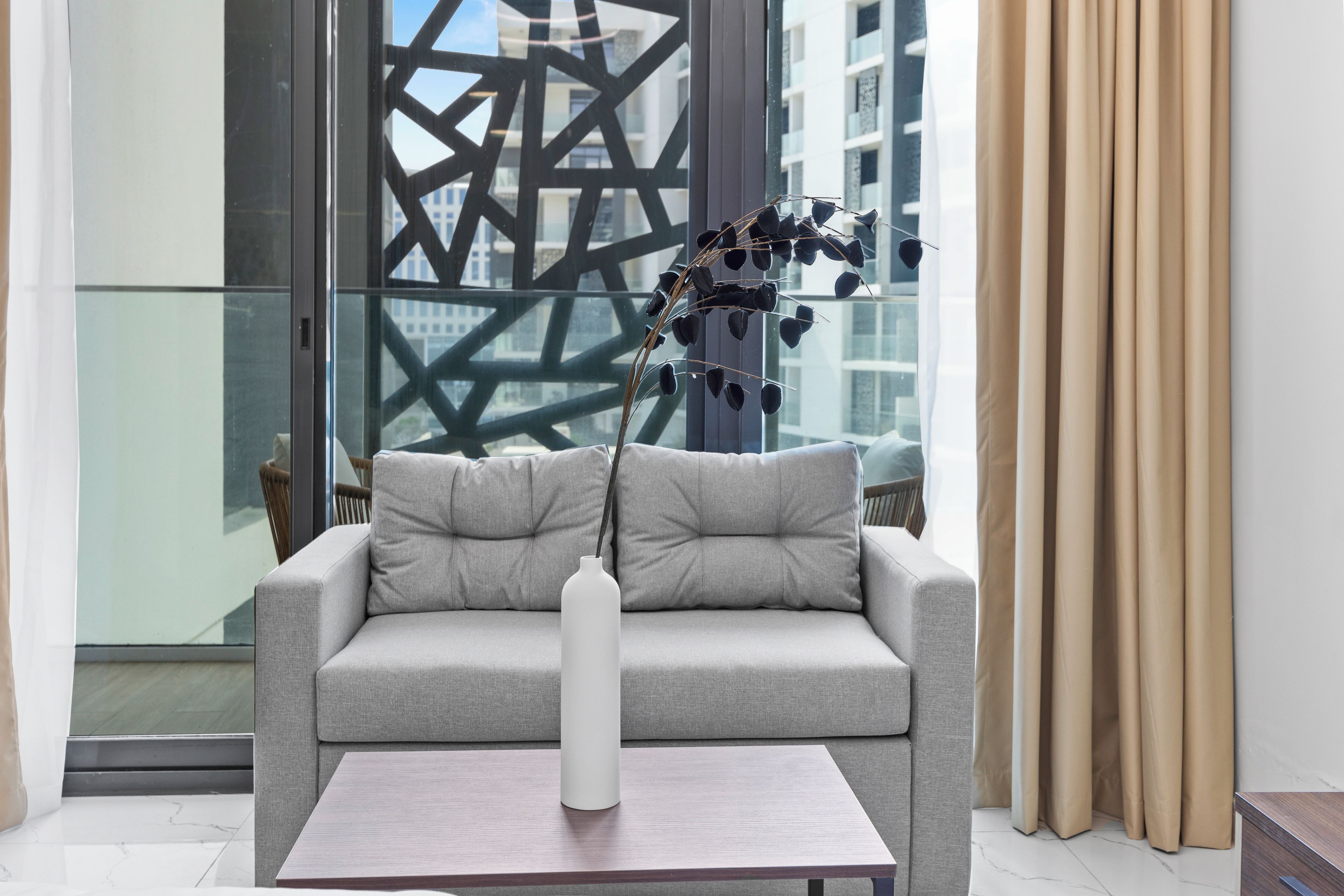 Un salon moderne avec un canapé gris, un vase blanc et une table basse en bois.
