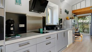 Una cocina moderna con estufa integrada, un lavaplatos y un lavamanos. Hay una ventana que proporciona luz natural y vistas al exterior.