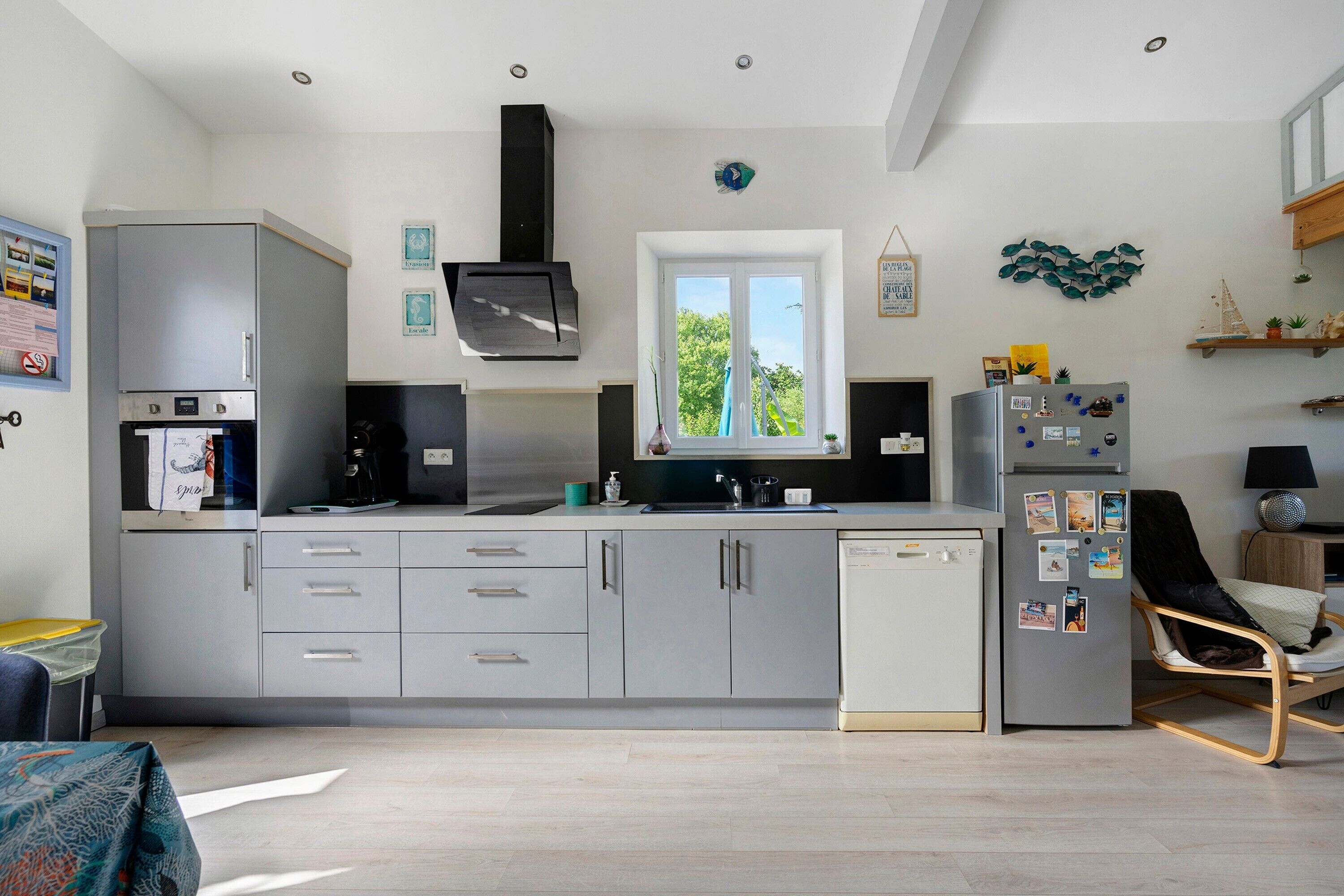 Una cocina moderna con lavavajillas integrado, armarios grises y una ventana con vistas.