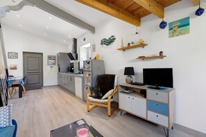 Ein modernes Wohnzimmer mit Holzboden, einem Essbereich, einer Küche und einem Fernseher auf einem Holzschrank.