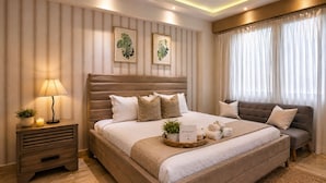 A modern bedroom with a large bed, bedside tables, a sofa, and a window with curtains.