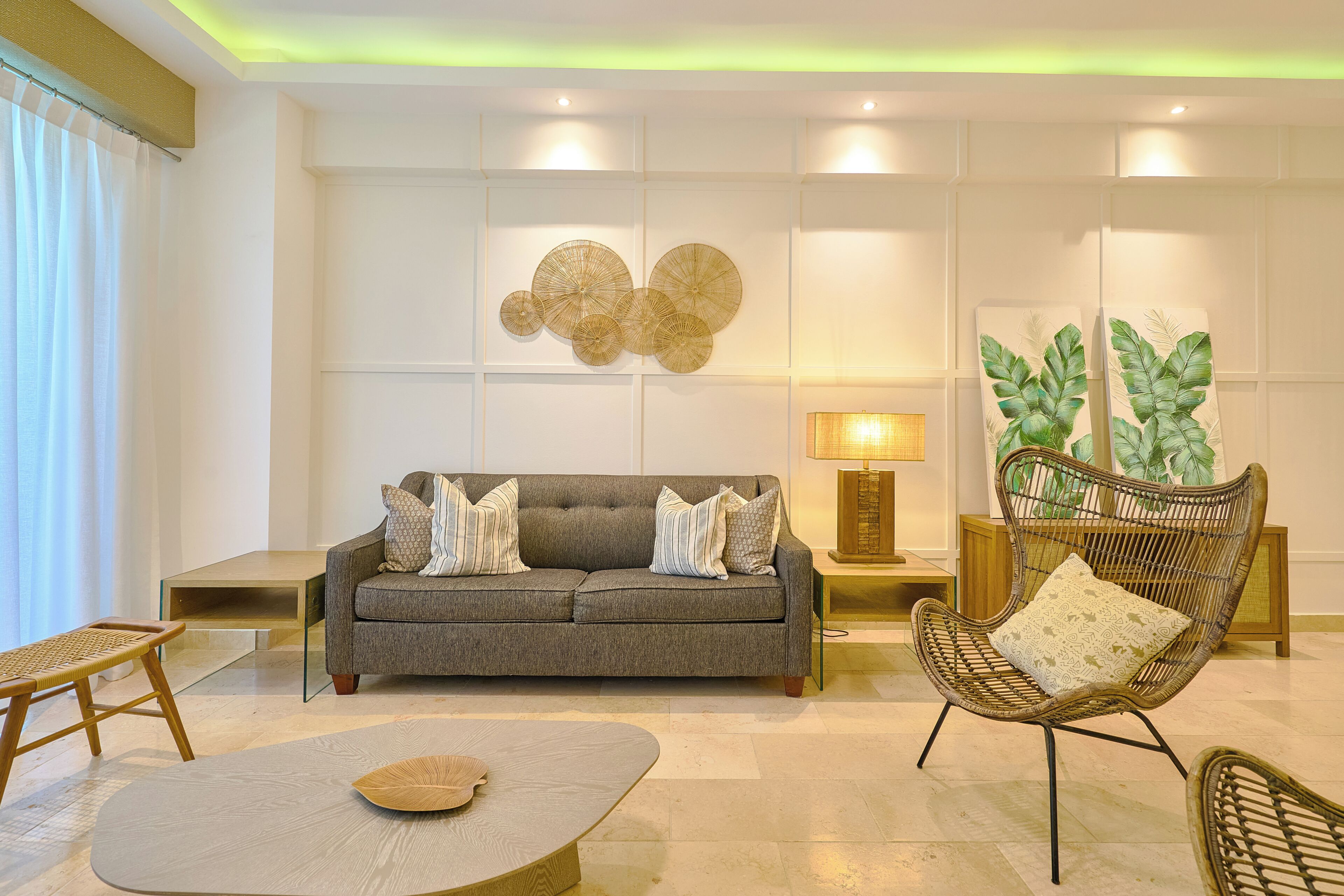 A modern living room with a grey sofa, a round coffee table, a wicker chair, and a wall with circular decorative panels.