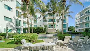A modern hotel with a pool, palm trees, and outdoor seating.