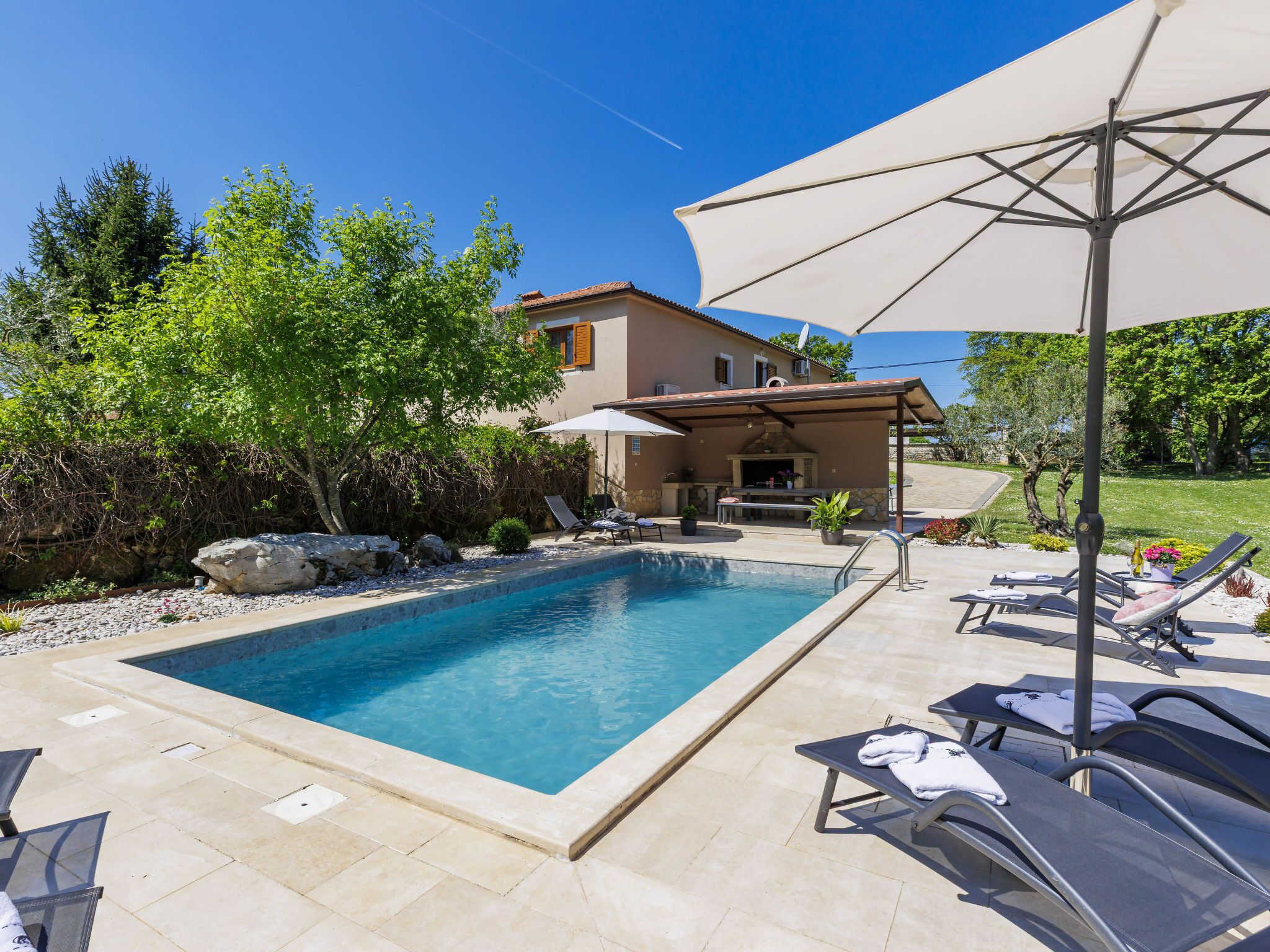 A swimming pool with lounge chairs and a patio umbrella.