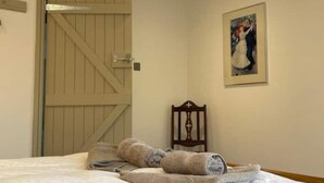 Et hotelværelse med en seng, en trädør, en stol og et billede i ramme på væggen.