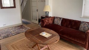 En stue med en brun lædersofa, et træbord og et mønstret tæppe.