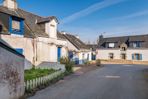 A quiet street with traditional houses, a clear sky, and a road leading into the distance.