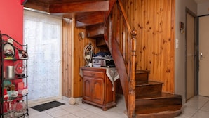A wooden staircase leading to a second floor, a wooden cabinet with various items, and a red wall. - Guest Room "Chez René et Christine - Room 1" with Wi-Fi (Damgan)