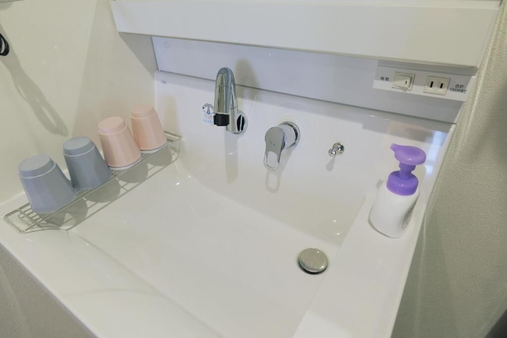 A bathroom sink with a faucet, a soap dispenser, and a cup holder with bottles.