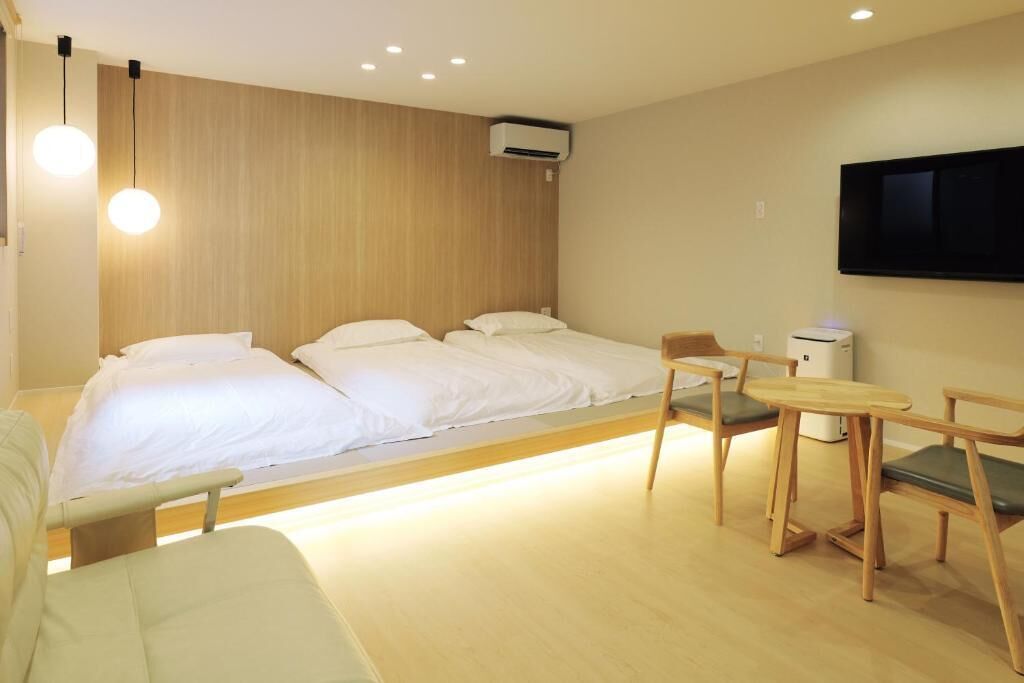 Ein Hotelzimmer mit zwei Betten, einem Fernseher, einem Schreibtisch und einem Sessel.