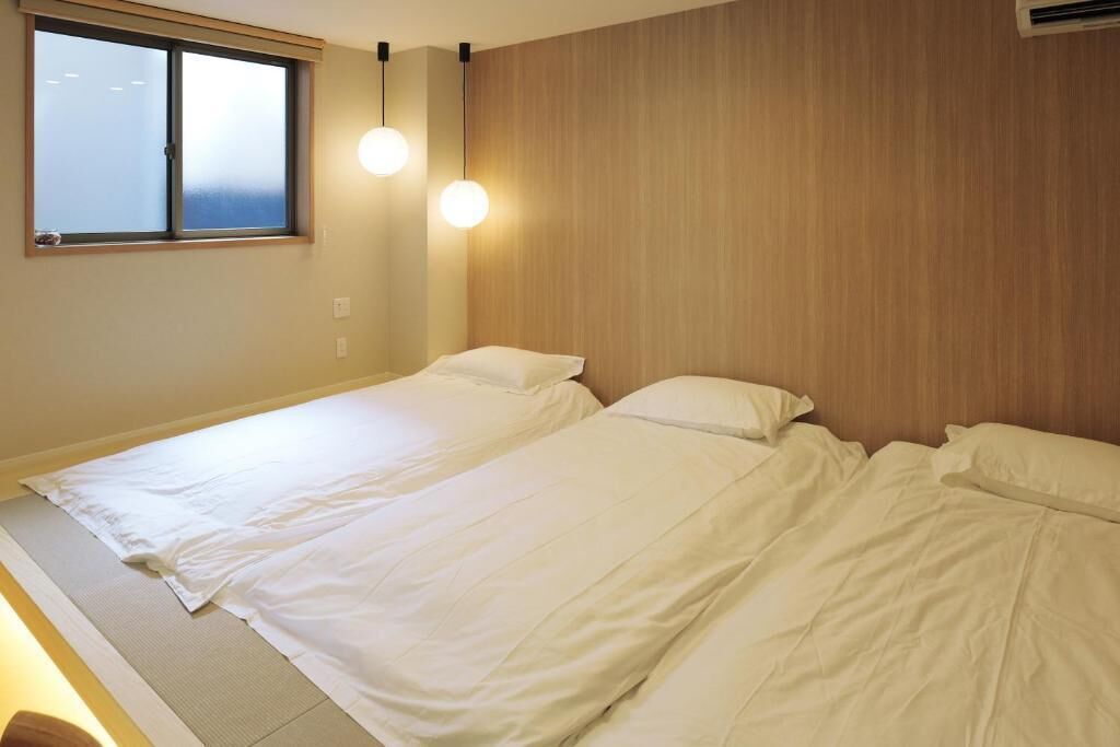 Un dormitorio con dos camas, una ventana y dos lámparas colgantes.