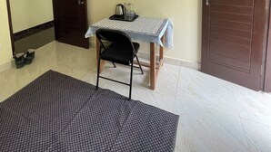 Una habitación con una mesa, una silla, un par de zapatos, un tapete, un espejo y dos puertas.