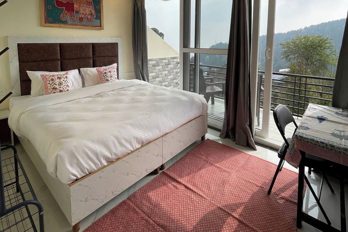 Een slaapkamer met een bed, een plafondventilator, een raam met gordijnen en uitzicht op de omgeving.