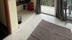 Una cocina moderna con un ventanal grande, un taburete rojo y vistas a un balcón.