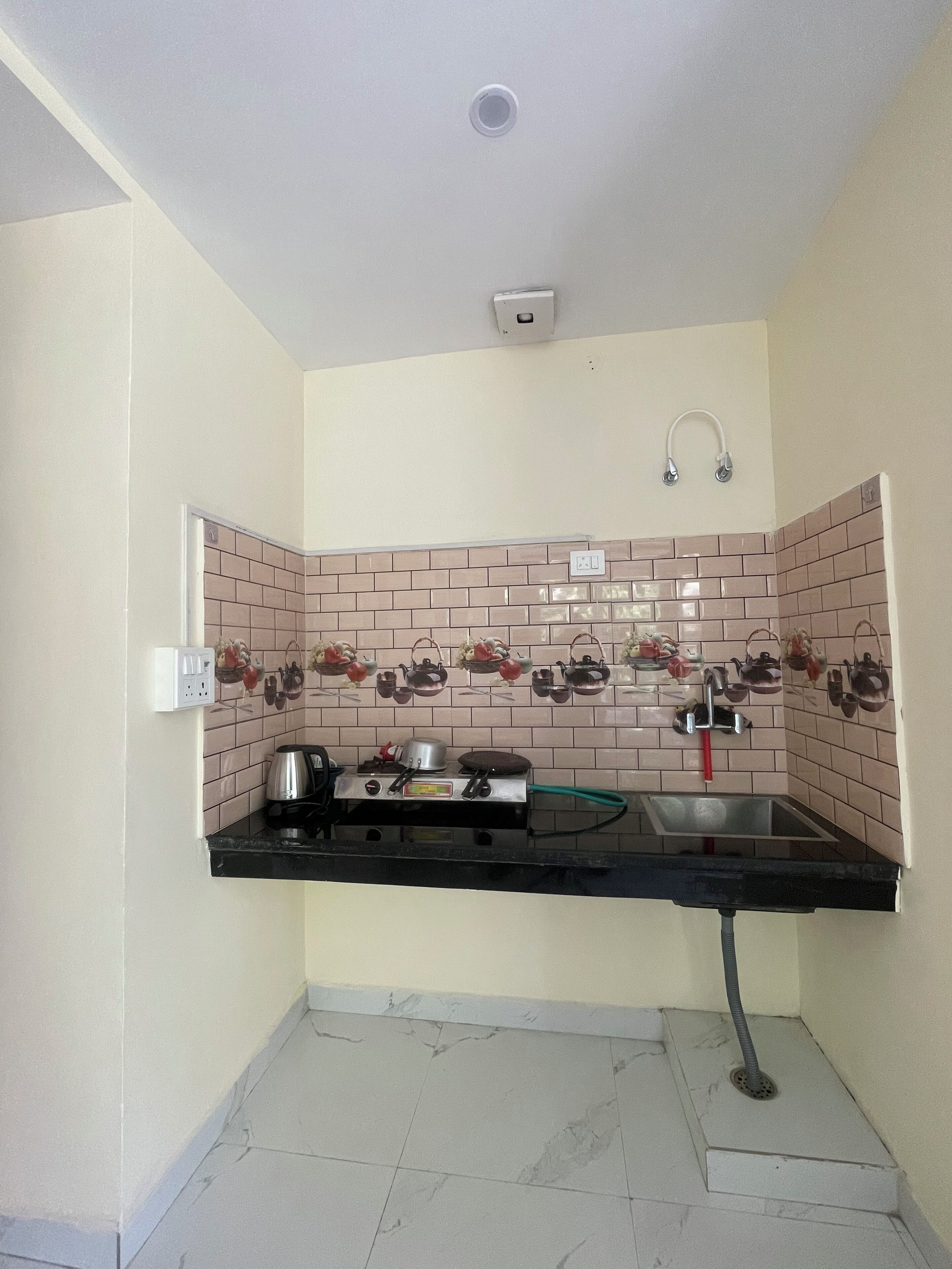 Una cocina compacta con estufa a gas, un lavamanos y un salpicadero de azulejos.