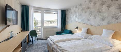 A hotel room with two beds, a desk, a chair, a TV, and a window with curtains.