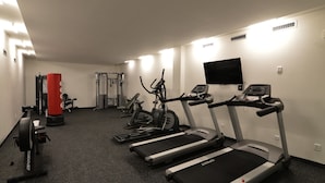 Ein Fitnessstudio mit Laufbändern, Crosstrainern und einem Boxsack.