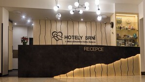 Ein Hotelrezeptionstresen mit modernem Design, ein Empfangsbereich und ein an der Wand befestigtes Schild.
