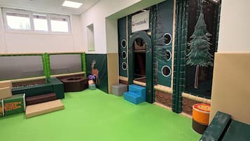 Espaço de recreação com piso verde, casinha e janela.