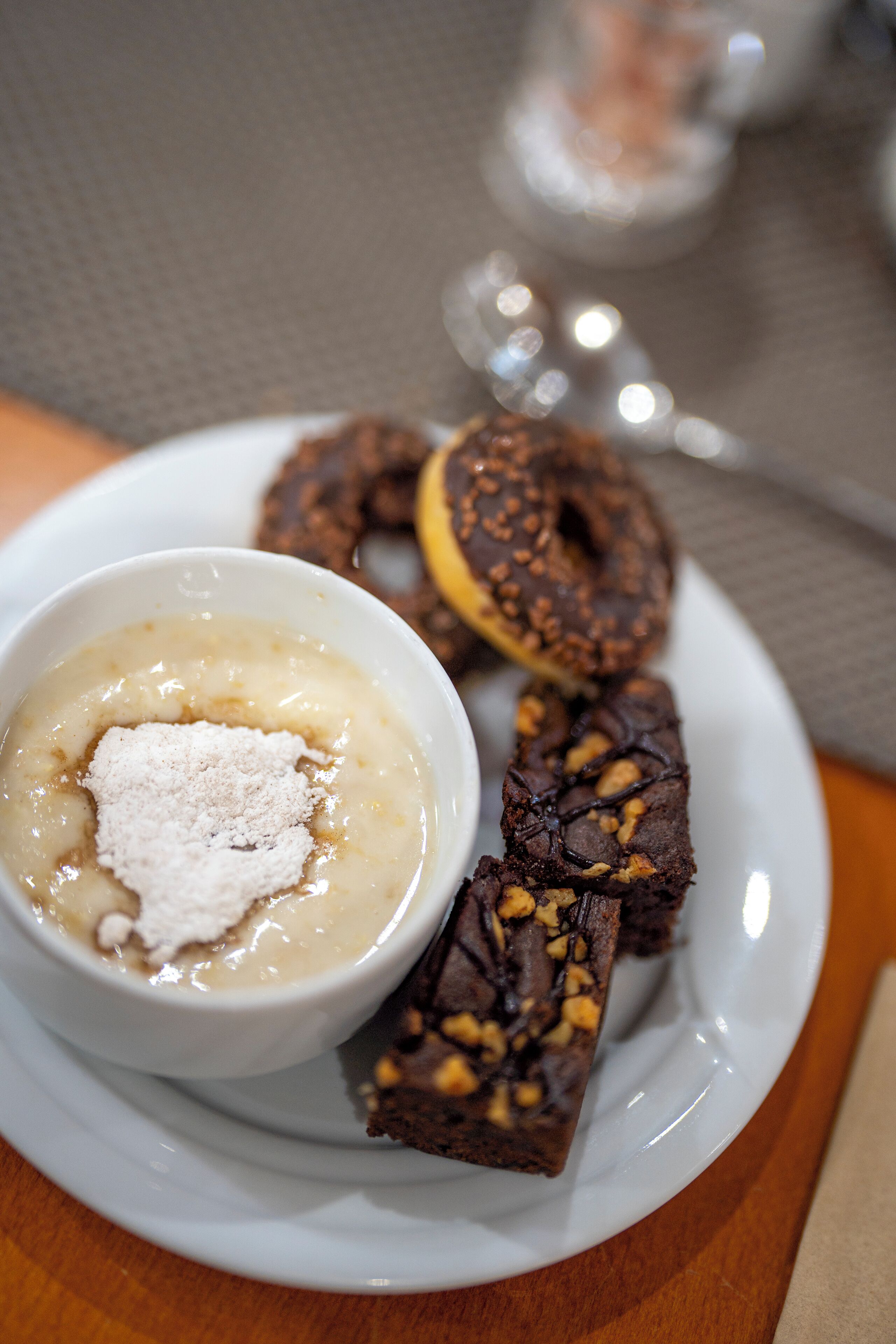 En tallerken med dessert bestående af en chokoladekage, en kringle og en skål med budding og topping.