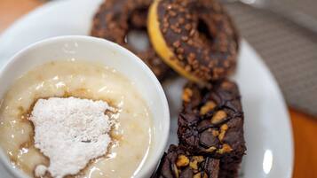 En tallerken med dessert bestående af en chokoladekage, en kringle og en skål med budding og topping.