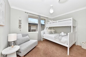 Ein Schlafzimmer mit Etagenbett, Sofa, Lampe und einem Fenster mit Vorhängen.