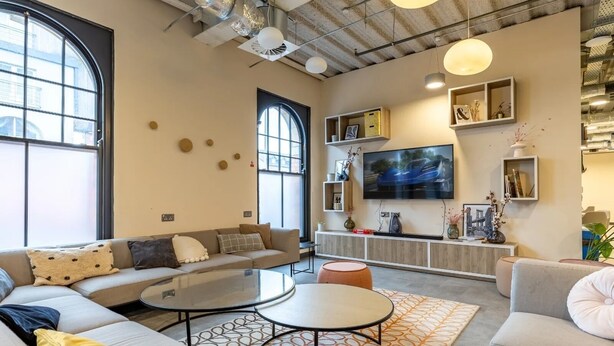 Ein modernes Wohnzimmer mit einer Sofagarnitur, einem Couchtisch und einem an der Wand montierten Fernseher.