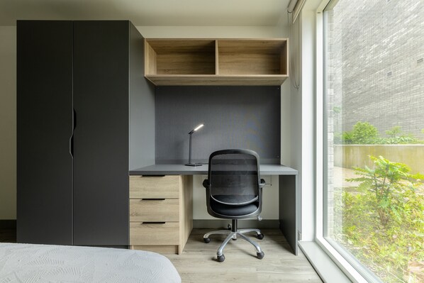 Un dormitorio moderno con una cama, un escritorio con silla y un armario.