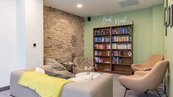A cozy reading area with a stone wall, a bookshelf filled with books, and comfortable seating.