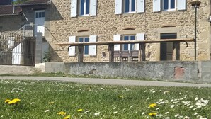 Un edificio de piedra con varias ventanas y un balcón, rodeado de un césped con flores.