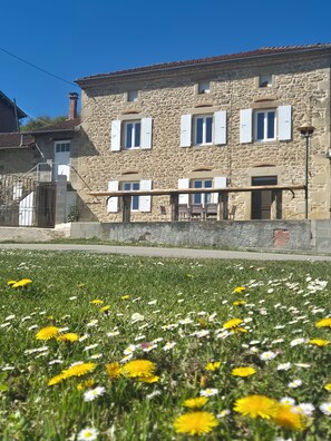 A stone building with multiple windows and a balcony, surrounded by a grassy area with flowers. - THE CHARM OF THE COUNTRYSIDE (Saint-Avit)