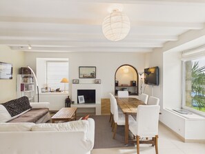 A modern living room with a fireplace, dining table, and white furniture. - House for 8 with garden and river view (La Trinité-sur-Mer)