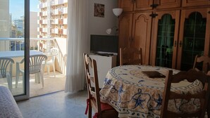 A room with a balcony, a dining table with chairs, a TV, and a wooden cabinet. - Studio 30 meters from the beach, Saint Raphaël, near TGV station and town center, parking. (Saint-Raphaël)