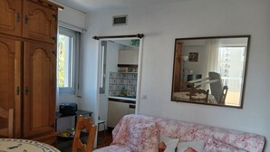 A room with a wooden wardrobe, a floral sofa, a round table with a patterned tablecloth, and a mirror on the wall. - Studio 30 meters from the beach, Saint Raphaël, near TGV station and town center, parking. (Saint-Raphaël)