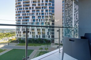 Un edificio moderno con varios pisos, ventanas amplias y un balcón con baranda de metal.