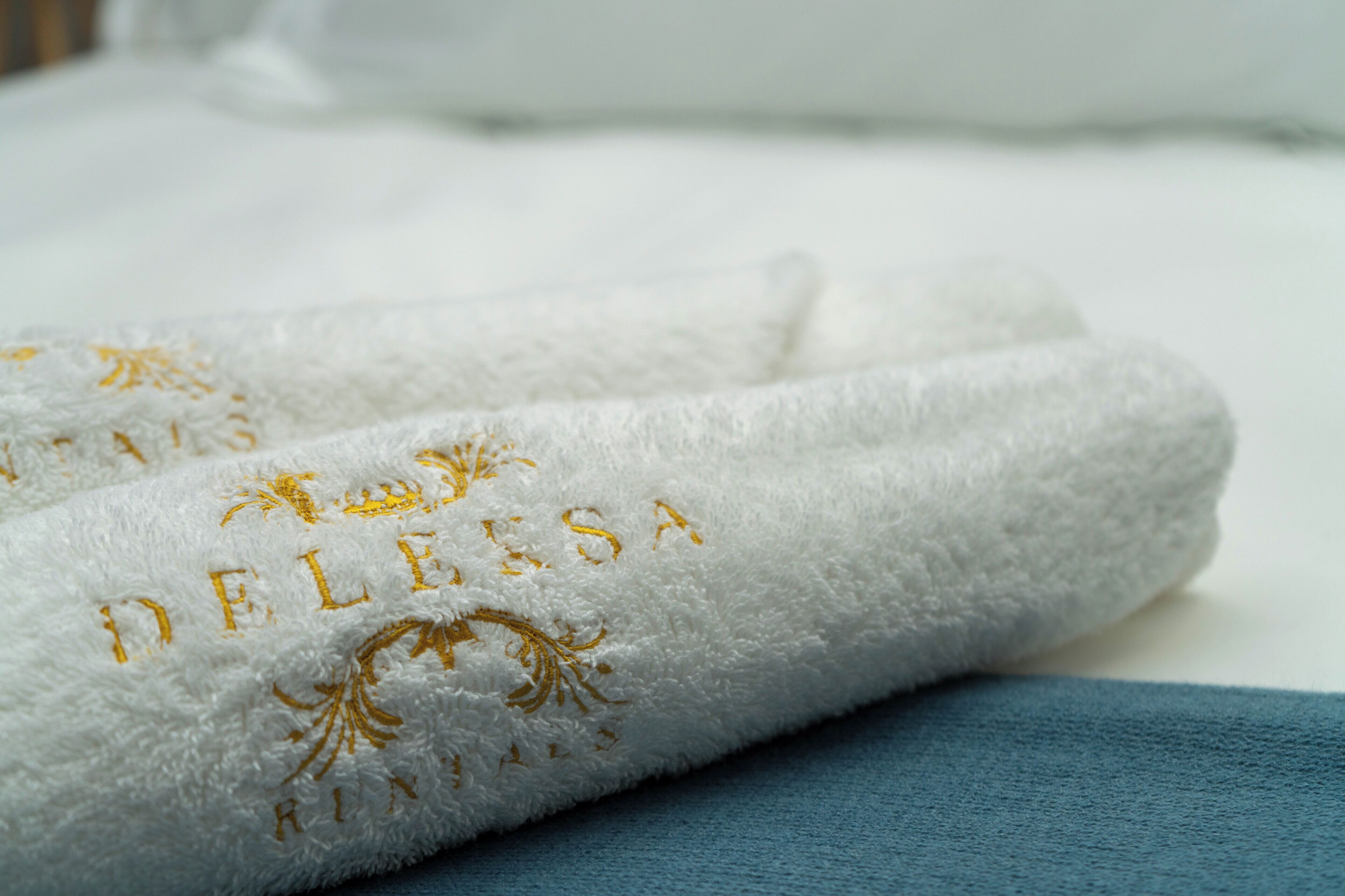A white towel with embroidered text and a blue cloth.