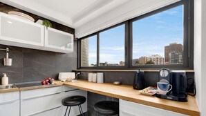 Eine moderne Küche mit einem großen Fenster, weißen Schränken und einer Holzarbeitsplatte.