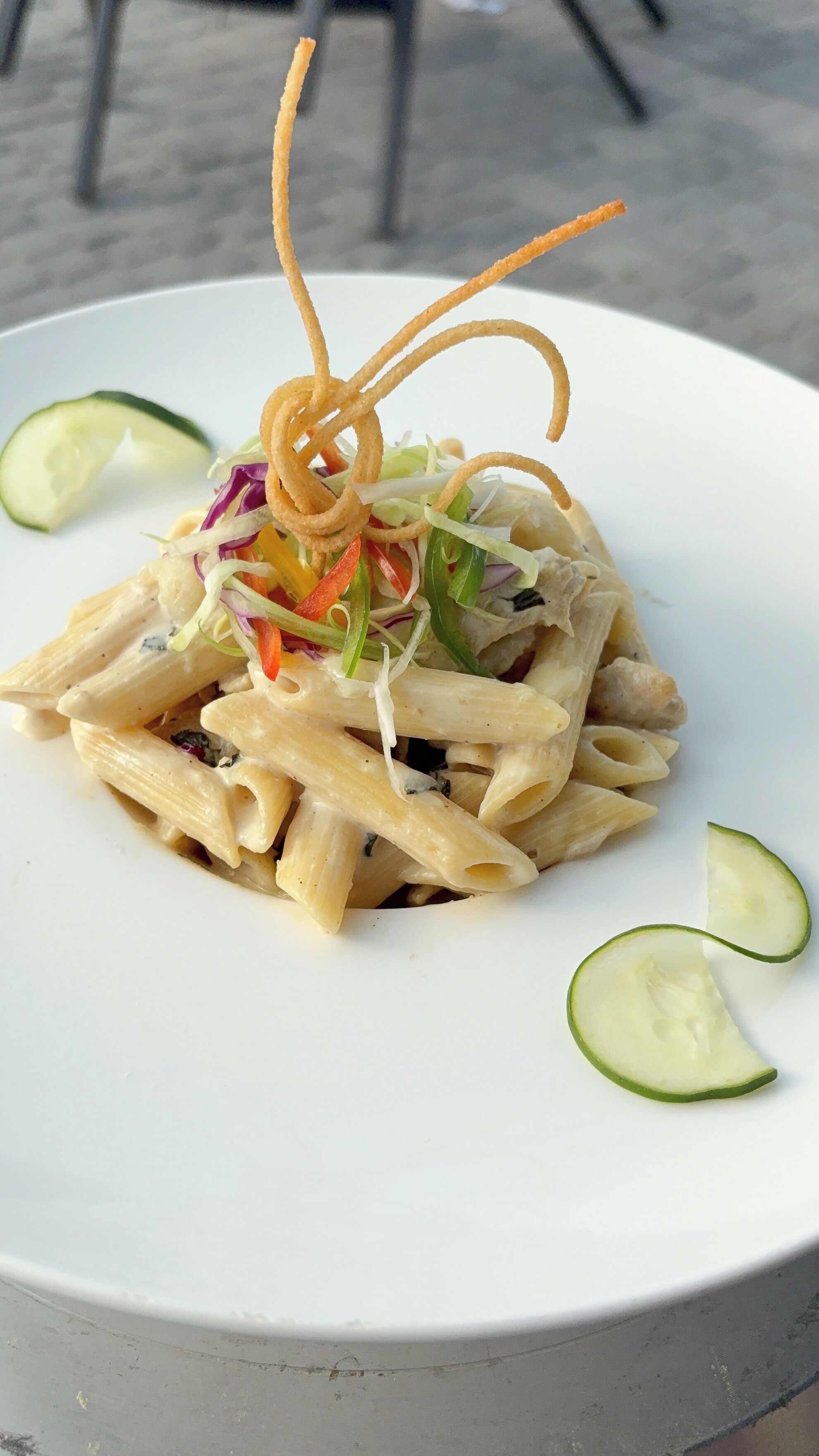Un piatto di pasta con verdure e guarnizione decorativa.