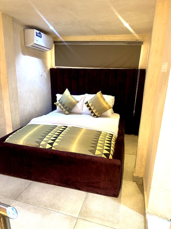 A bed with a dark headboard, white bedding, and patterned pillows. - 234lofts resort (Lekki)